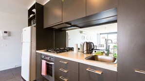 A modern kitchen with a built-in oven, a stainless steel sink, and a stove. - ERICA, 2BDR South Yarra Apartment (South Yarra)