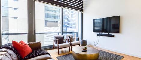 A modern living room with a leather sofa, a round coffee table, and a flat-screen TV mounted on the wall.