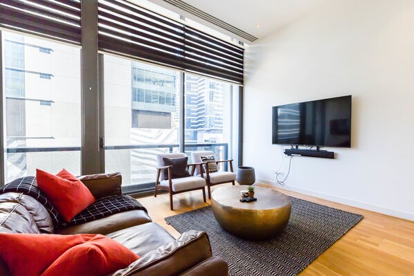 Un salon moderne avec un canapé en cuir, une table basse ronde et un téléviseur à écran plat fixé au mur.