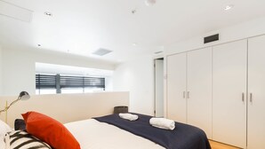 A modern hotel room with a large bed, a wardrobe, and a window with blinds. - EVAN, 1BDR Southbank Apartment (Southbank)