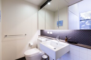 Un baño moderno con inodoro, lavamanos y espejo.