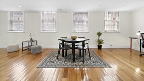 A dining area with a round table, four chairs, a central bowl, and a patterned rug. - HELENA, 2BDR Fitzroy House (Fitzroy)