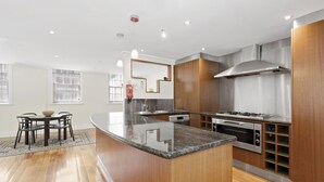 A modern kitchen with a central island, stainless steel appliances, and wooden cabinetry. - HELENA, 2BDR Fitzroy House (Fitzroy)