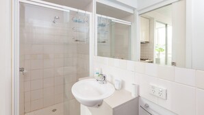 Un baño moderno con ducha, lavamanos y espejo.