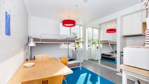 Una habitación pequeña con una cama litera, una mesa de comedor y una kitchenette.