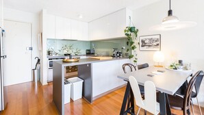 Une cuisine moderne avec des meubles blancs, un îlot central et un coin repas comprenant une table et des chaises.
