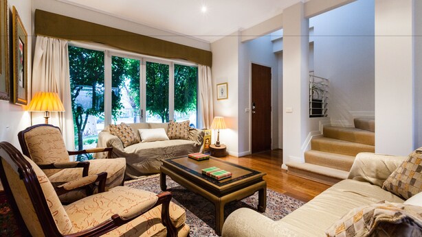 A spacious living room with a sofa set, a coffee table, and a fireplace. There is a staircase leading to an upper level. - JASMINE, 2BDR Port Melbourne House (Port Melbourne)