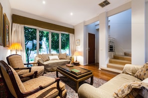 A spacious living room with a sofa set, a coffee table, and a fireplace. There is a staircase leading to an upper level. - JASMINE, 2BDR Port Melbourne House (Port Melbourne)
