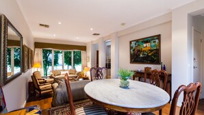 A dining area with a round marble table, wooden chairs, and a potted plant. - JASMINE, 2BDR Port Melbourne House (Port Melbourne)