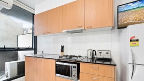 Una cocina moderna con armarios de madera, horno empotrado, microondas, estufa a gas y refrigerador.