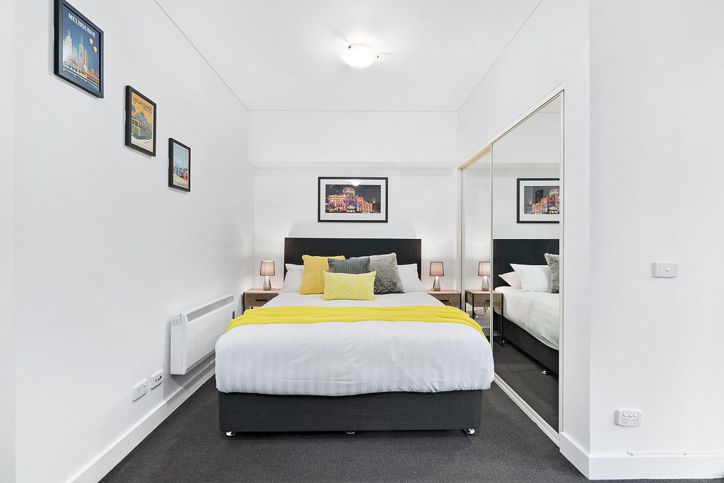A modern bedroom with a large bed, bedside tables, and a mirror.