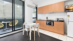 Una cocina moderna con armarios de madera, horno empotrado y comedor con mesa y sillas.