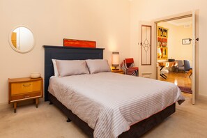 Restful retreat with a large bed, nightstand, and mirror, surrounded by a cozy seating area and decorative artwork.