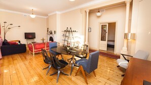 A modern living room with a dining table, chairs, a sofa, and a TV.