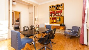 A dining area with a glass table, blue upholstered chairs, and a modern chandelier.