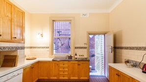 A kitchen with wooden cabinets, a white countertop, a window with a view of bicycles, and a patterned floor.