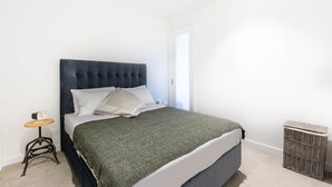 Una cama bien hecha con un cabecero oscuro, una manta verde y ropa de cama blanca.