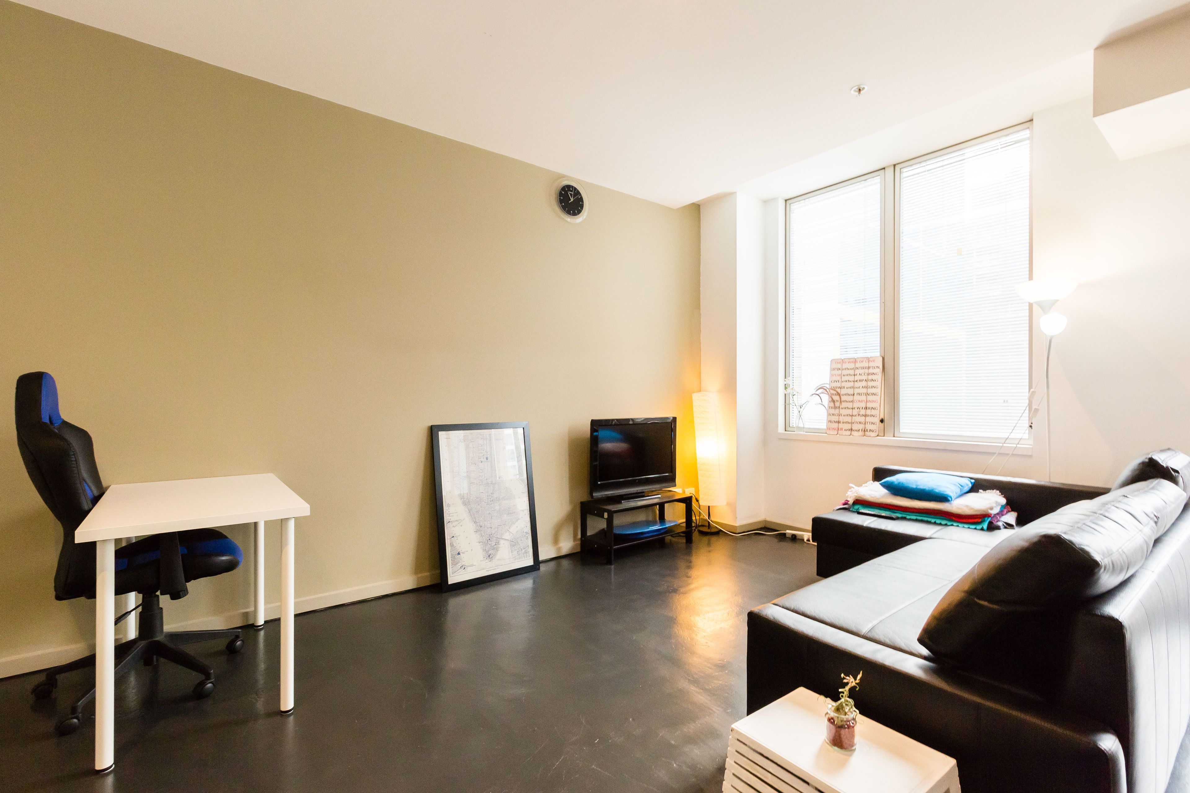 Una sala de estar moderna con un televisor de pantalla plana, una silla gamer, un sofá y una pequeña mesa.