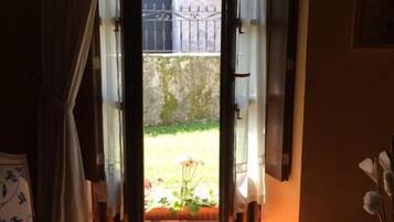 Una habitación con cama, una silla y vistas a un jardín por una puerta abierta.