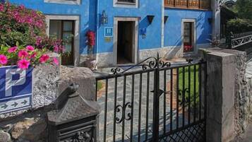 Un edificio de dos pisos con fachada azul, balcones con barandillas de madera y una entrada con portón.