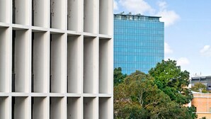 A modern building with a grid-like facade and a large glass structure in the background. - SIENNA, 1BDR South Melbourne Apartment (South Melbourne)