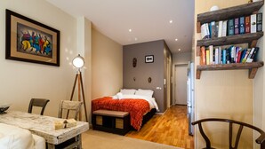 Een slaapkamer met een bed, nachtkastje en een boekenplank.