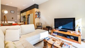 Een moderne woonkamer met een grote flatscreen televisie, een bank, een salontafel en een boekenkast.