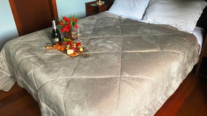 Ein ordentlich bezogenes Bett mit einer gesteppten Decke, ein Nachttisch mit Lampe und ein Tablett mit Speisen und Getränken auf dem Bett.