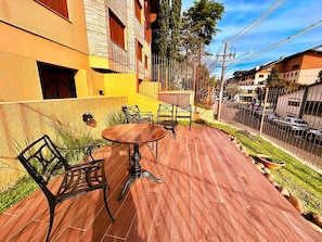 Un patio al aire libre con una mesa redonda y sillas, una cerca de metal y un edificio con fachada amarilla.
