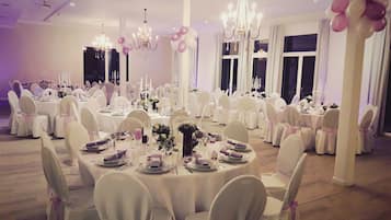 A banquet hall with round tables, white tablecloths, and chairs with pink sashes.