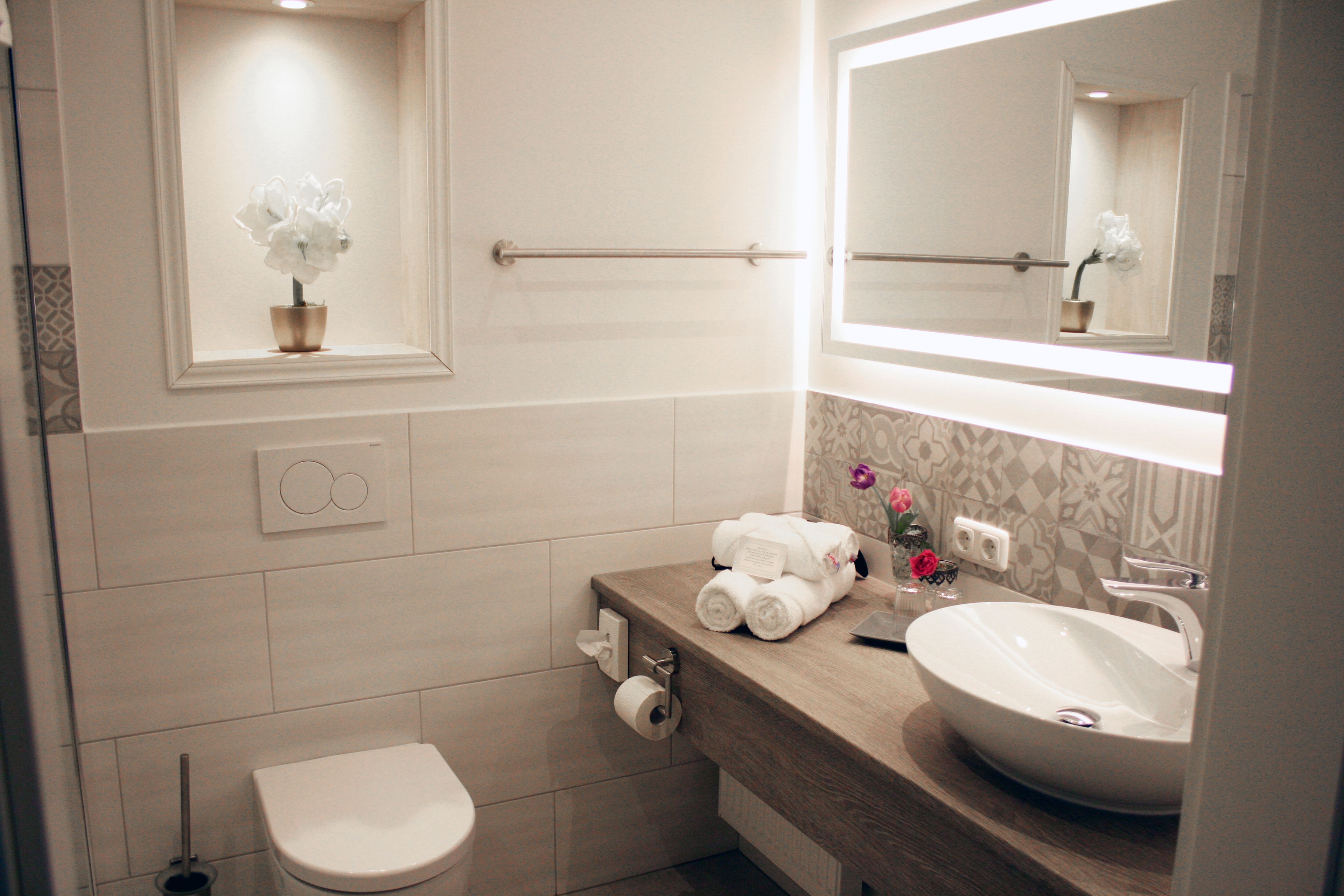 Ein modernes Badezimmer mit Toilette, Waschbecken und Spiegel.