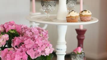 Un expositor blanco escalonado con cupcakes y flores rosas.