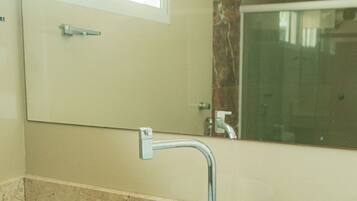 A bathroom with a white sink, a mirror, and a shower.