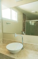 A bathroom with a white sink, a mirror, and a shower.