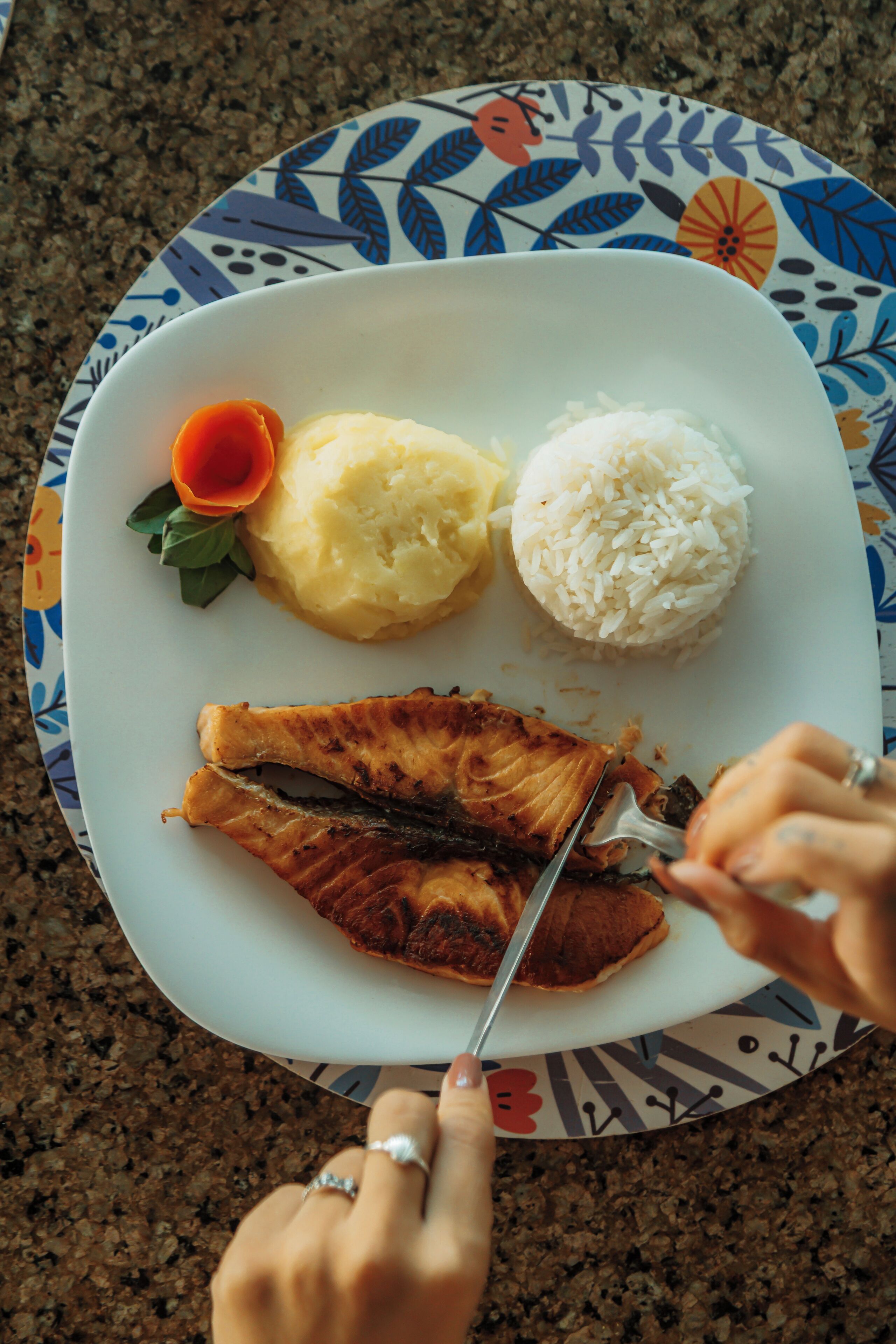 A plate with salmon, mashed potatoes, and rice, and a carrot garnish.