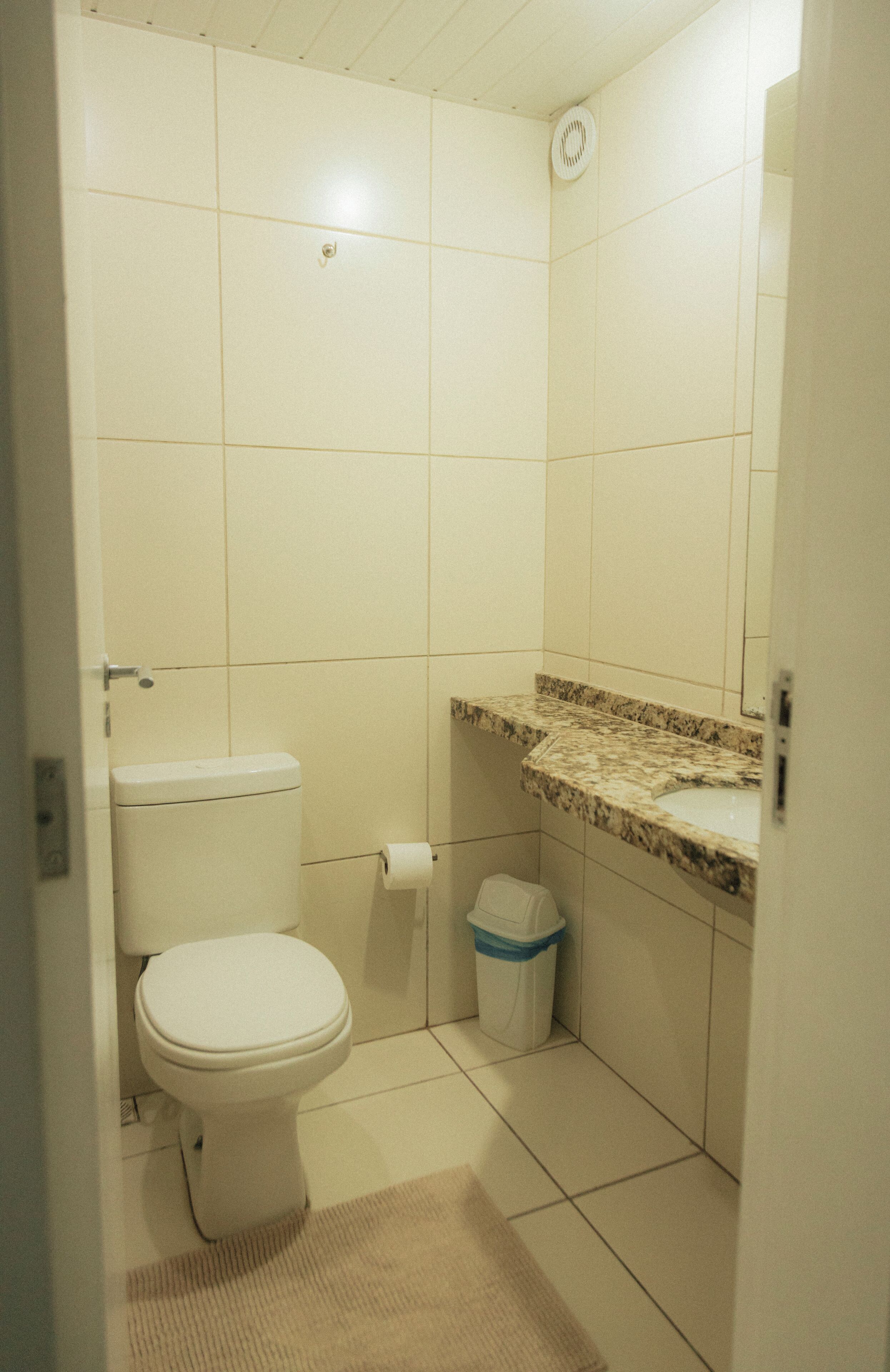 A small, clean bathroom with a toilet, a sink, and a trash bin.