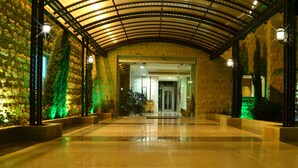 A spacious, well-lit hallway with a curved ceiling, stone walls, and green-lit plants. - Monteverde Hotel (Beit Mery)