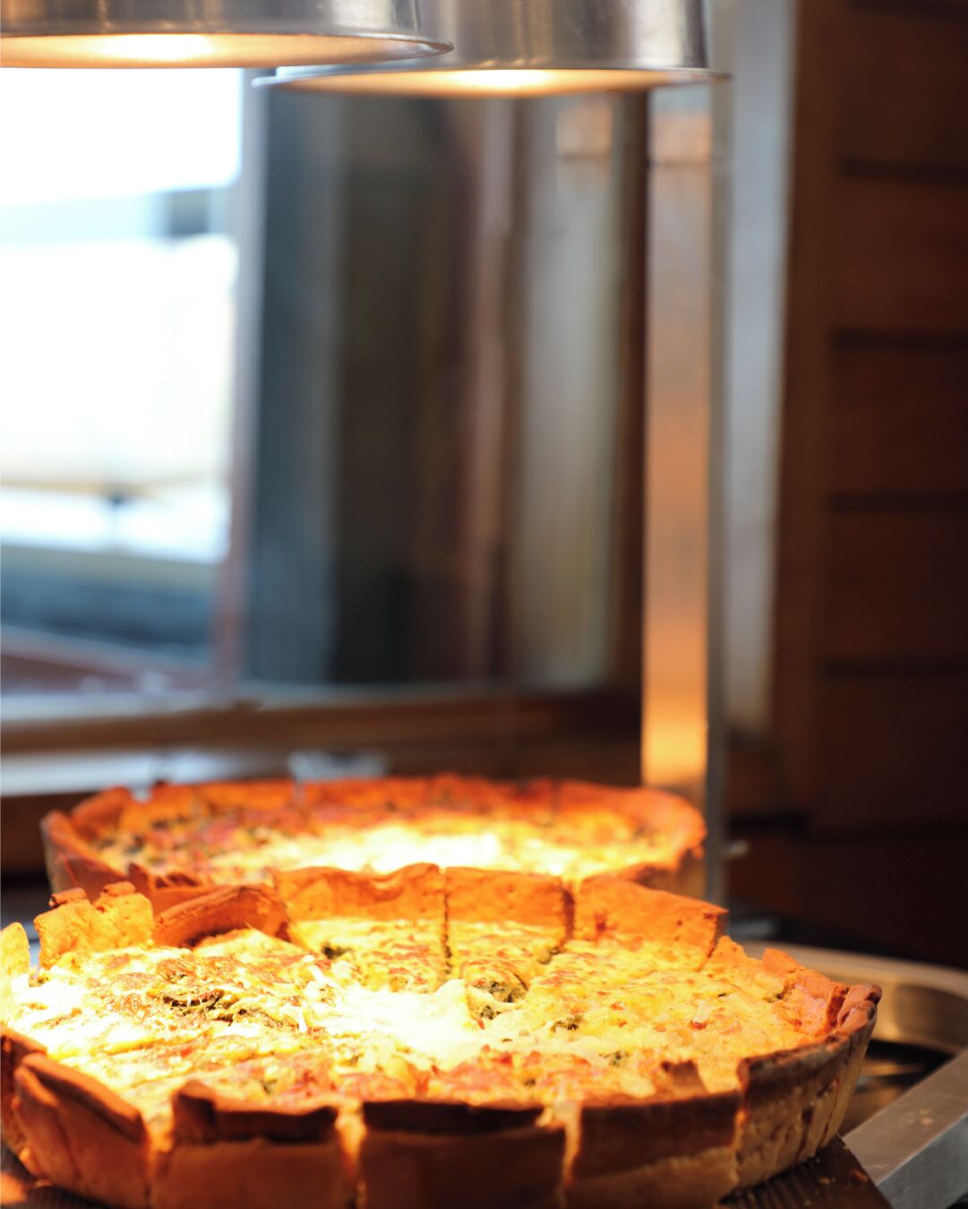 Une pizza dans un plat en métal, probablement dans une cuisine ou dans un espace dédié à la préparation des aliments.