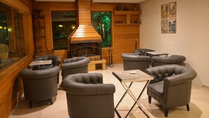 A modern interior with a fireplace, leather armchairs, and a dining area. - Monteverde Hotel (Beit Mery)
