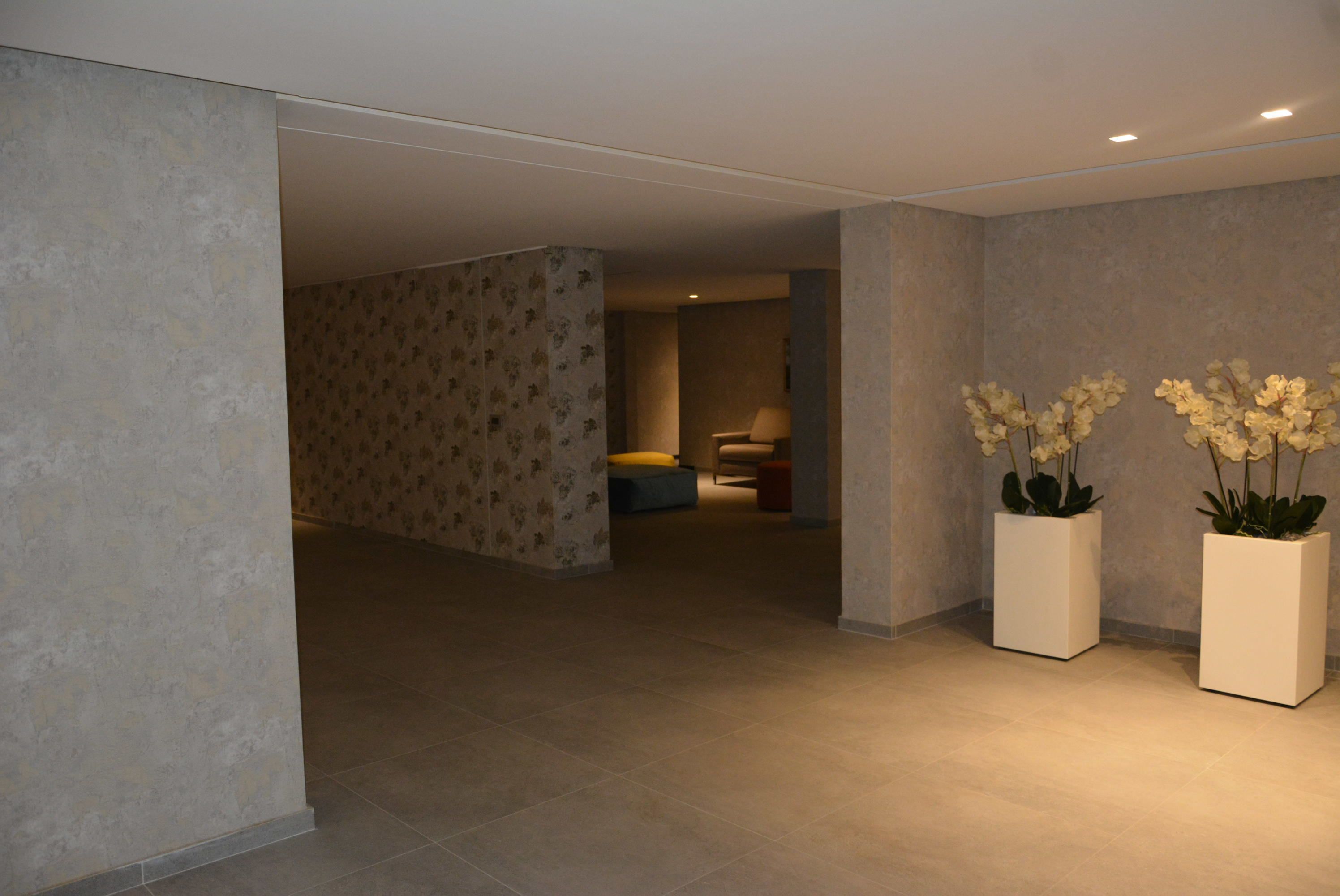 Eine moderne Hotelhalle mit einer gedeckten Farbpalette, einem gefliesten Boden und zwei Blumentöpfen.