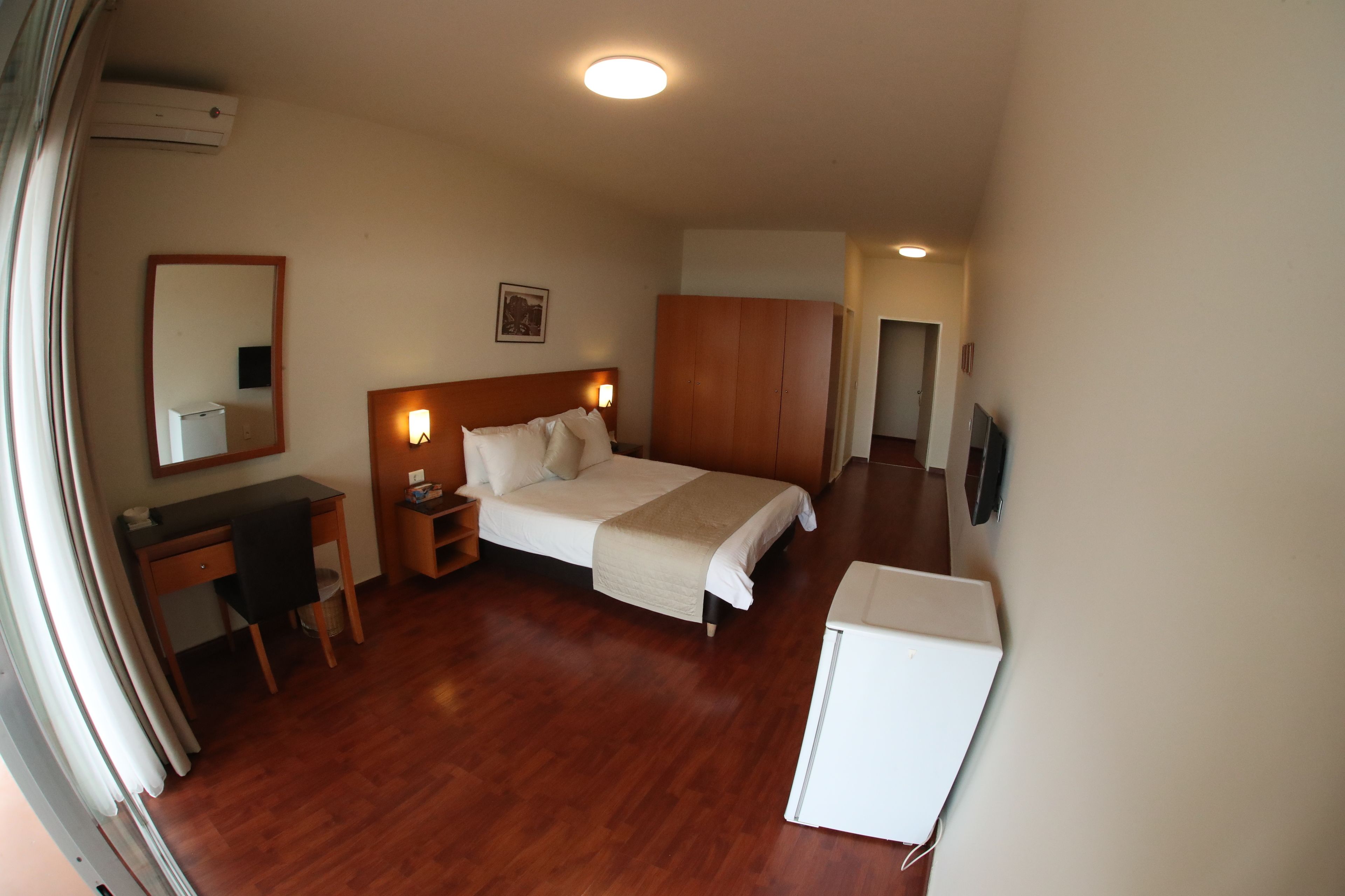 Ein Hotelzimmer mit einem Bett, einem Schreibtisch, einem Kleiderschrank und einem Fernseher.