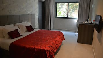 A bedroom with a large bed, a desk, and a window with curtains.