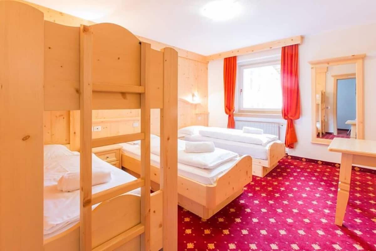 Une chambre avec des lits superposés, une moquette rouge et une fenêtre avec des rideaux rouges.