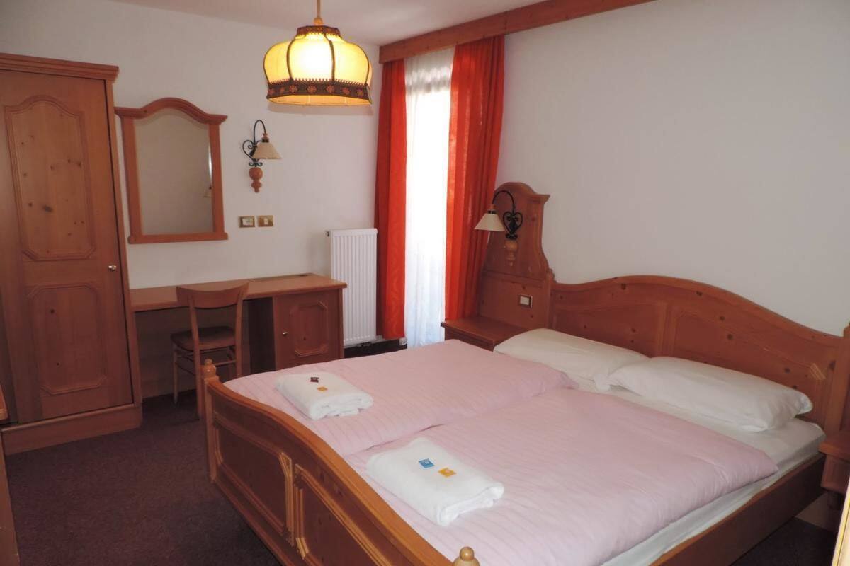 Une chambre à coucher avec un lit double, une armoire en bois, un bureau avec une chaise, un miroir et un radiateur.