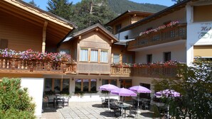 Un chalet traditionnel doté de balcons en bois, d’un espace extérieur aménagé et de jardinières fleuries.