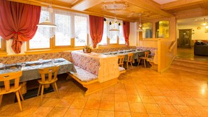 Un restaurant au décor intérieur en bois, avec un long comptoir et différents types de sièges, notamment des bancs et des chaises.