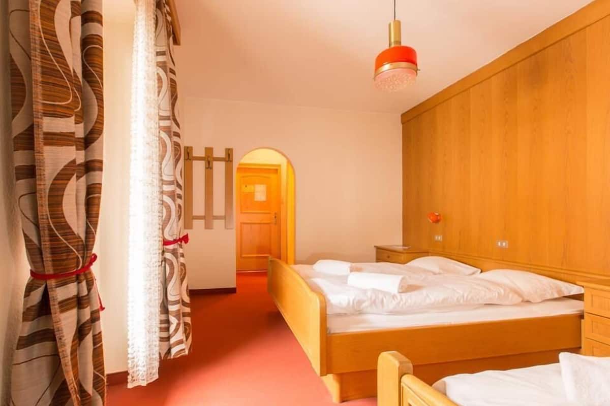 Une chambre d’hôtel avec deux lits en bois, une lampe suspendue rouge et une armoire en bois.