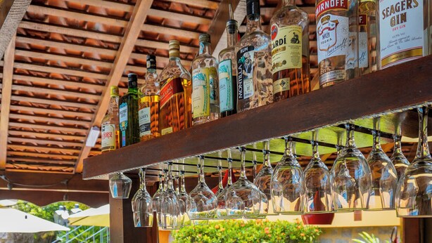 A bar area with a stone counter, various liquor bottles, and a fruit display. - Pousada do Forte (Paraty)
