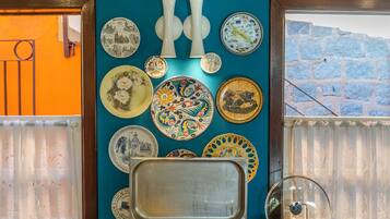Un tavolo per buffet con diversi piatti, una parete decorata con piatti e una finestra vista su un muro di pietra.