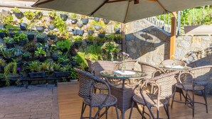 A patio area with wicker furniture and a stone wall with potted plants. - Pousada do Forte (Paraty)